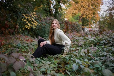 Şirin kız bahçede oturuyor ve gülümsüyor.