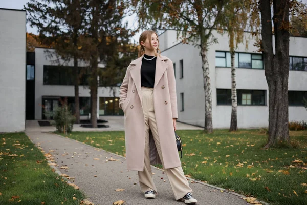 Güzel paltolu genç bir kız sokakta duruyor.