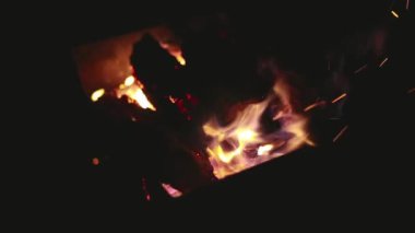 Bir adam ateşin içinde kütükleri düzeltir.