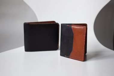 Deri cüzdan kahverengi ve siyah, beyaz arka planda deri işleme araçları, deri eşyalar.