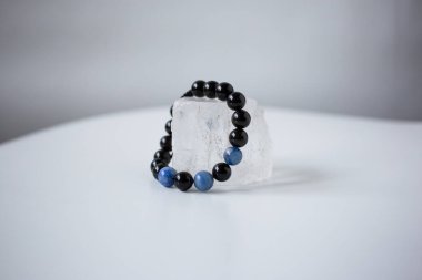 Çok renkli doğal taşların boncukları kar beyazı bir taşın üzerinde bulunur.