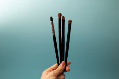 Mavi arka planda makyaj fırçaları