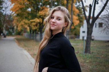 Siyah kazaklı ve zincirli bir kız kameraya bakıyor.