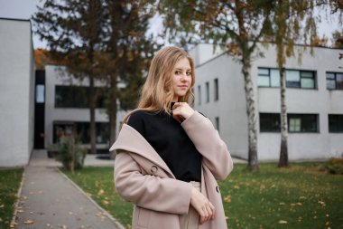 Güzel ceketli genç kız kameraya bakıyor.