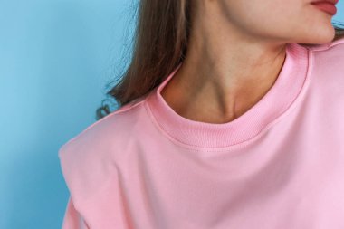 Şık giyimli bir kız, parlak bir arka plan karşısında rahat bir spor giyim, bir dergi için stüdyo çekimi, kumaş ve çiçeklerle ilgili detaylar.