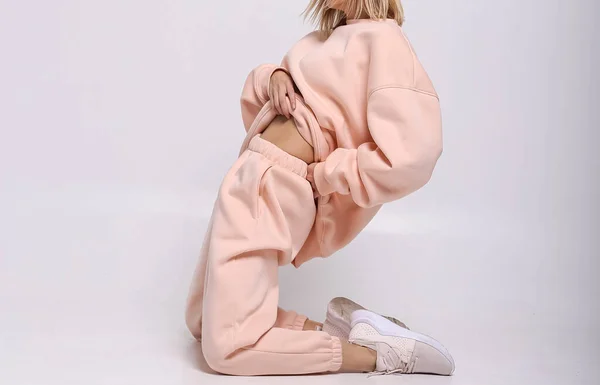 Şık giyimli bir kız, parlak bir arka plan karşısında rahat bir spor giyim, bir dergi için stüdyo çekimi, kumaş ve çiçeklerle ilgili detaylar.