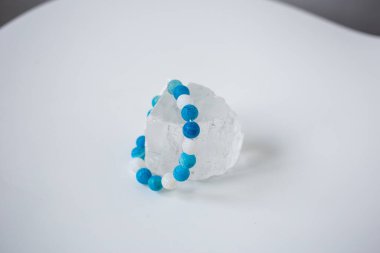 Çok renkli doğal taşların boncukları kar beyazı bir taşın üzerinde bulunur.