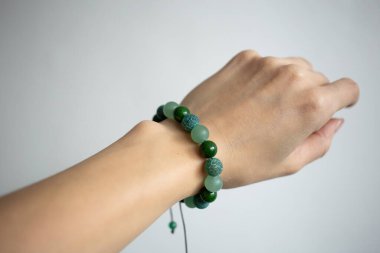 Farklı renklerde doğal taşlarla bilezik beyaz arka planda genç bir kızın güzel elinde.