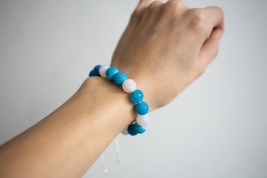 Farklı renklerde doğal taşlarla bilezik beyaz arka planda genç bir kızın güzel elinde.