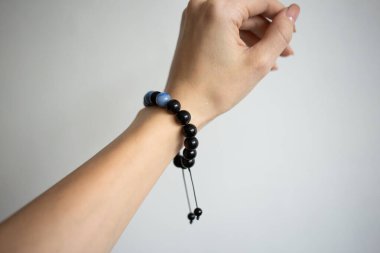 Farklı renklerde doğal taşlarla bilezik beyaz arka planda genç bir kızın güzel elinde.