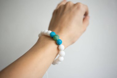 Farklı renklerde doğal taşlarla bilezik beyaz arka planda genç bir kızın güzel elinde.