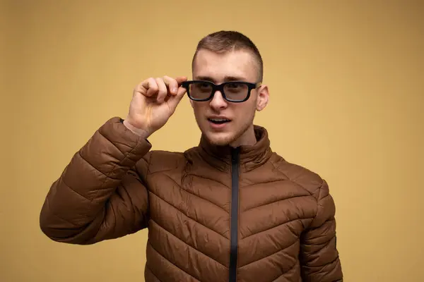 Ung Man Årsåldern Brun Jacka Gul Bakgrund Justerar Sina Glasögon — Stockfoto