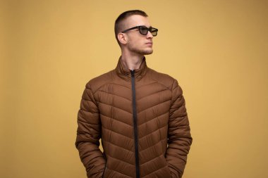 20 'li yaşlarda, kahverengi ceketli, sarı arka planda, üzgün, 3D film izlerken gözlük takan genç bir adam,