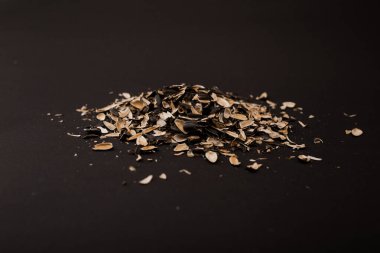 Tohumların altından bir kabuk dağı uzanır siyah bir arkaplanda.