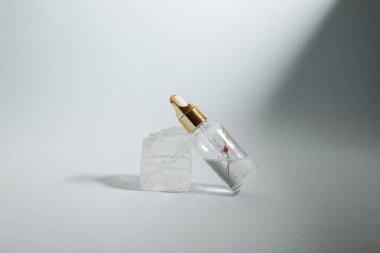 Bir şişe bakım kozmetiği, yağ, serum, arka planda ışığın altında duruyor, kadınlar için bir ürünün reklamını yapma kavramı.