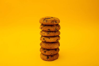 Çikolata parçacıklı kurabiyeler sarı arka planda yatıyor, minimalizm, tatlı, yiyecek