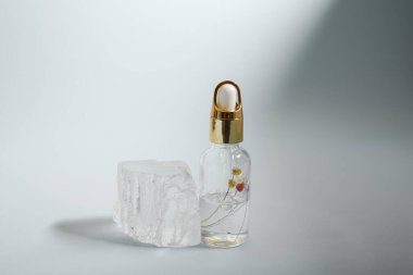 Bir şişe bakım kozmetiği, yağ, serum, arka planda ışığın altında duruyor, kadınlar için bir ürünün reklamını yapma kavramı.