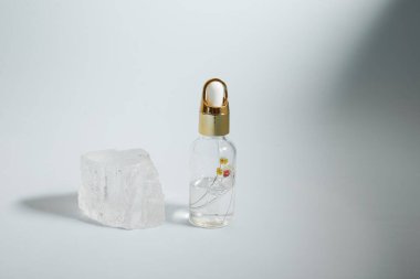 Bir şişe bakım kozmetiği, yağ, serum, arka planda ışığın altında duruyor, kadınlar için bir ürünün reklamını yapma kavramı.