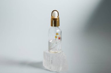 Bir şişe bakım kozmetiği, yağ, serum, arka planda ışığın altında duruyor, kadınlar için bir ürünün reklamını yapma kavramı.