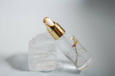 Bir şişe bakım kozmetiği, yağ, serum, arka planda ışığın altında duruyor, kadınlar için bir ürünün reklamını yapma kavramı.