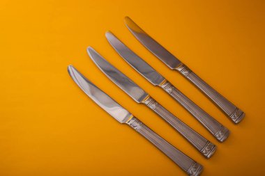 Knives made of metal, silver, lie on a yellow background