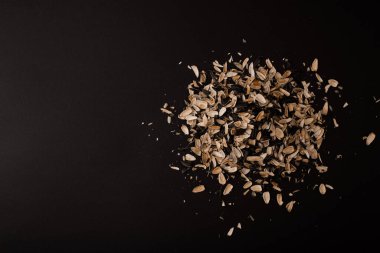 Tohumların altından bir kabuk dağı uzanır siyah bir arkaplanda.