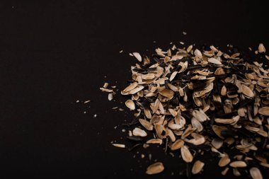 Tohumların altından bir kabuk dağı uzanır siyah bir arkaplanda.