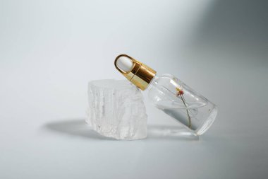 Bir şişe bakım kozmetiği, yağ, serum, arka planda ışığın altında duruyor, kadınlar için bir ürünün reklamını yapma kavramı.