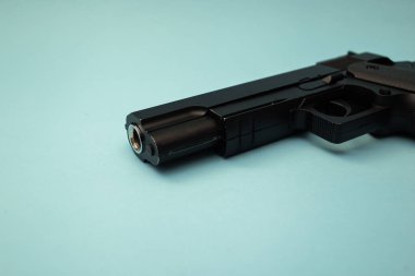 Büyük, güzel, siyah tabanca mavi arka planda yatıyor.