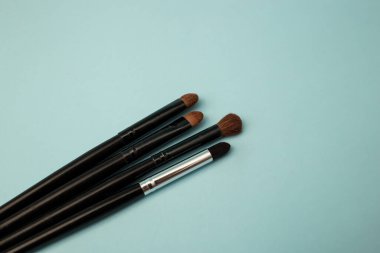 Mavi arka planda makyaj fırçaları