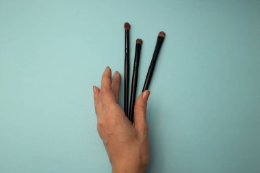 Mavi arka planda makyaj fırçaları