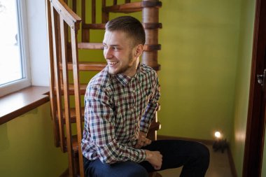 Ekose gömlekli adam gülümseyip gülüyor.