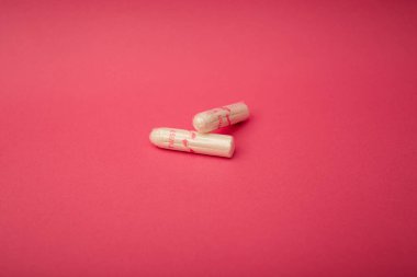 Medical female tampon on a pink background. Hygienic white tampon for women. Cotton swab. Menstruation, means of protection.