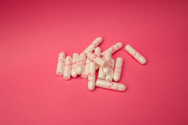 Medical female tampon on a pink background. Hygienic white tampon for women. Cotton swab. Menstruation, means of protection.