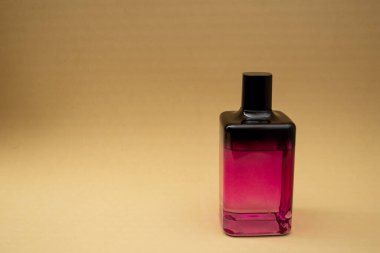 Bej bir arka planda pembe bir şişede parfüm