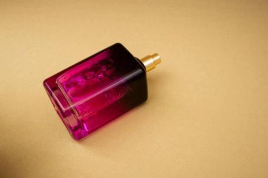 Bej bir arka planda pembe bir şişede parfüm