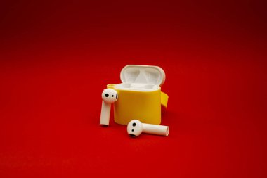 Kırmızı arka planda sarı kablosuz kulaklık.