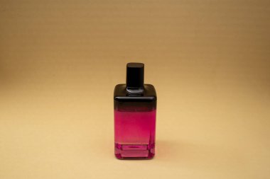 Bej bir arka planda pembe bir şişede parfüm