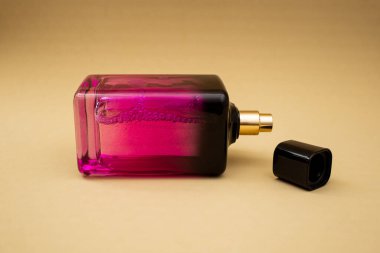 Bej bir arka planda pembe bir şişede parfüm