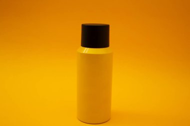 Sarı şişe sarı arka planda duruyor.