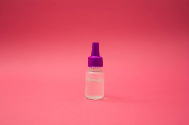 Pembe arka planda küçük bir kozmetik şişesi.