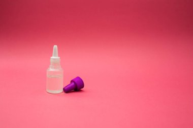 Pembe arka planda küçük bir kozmetik şişesi.