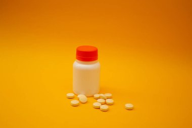 Sarı arka planda hapları olan kavanoz.