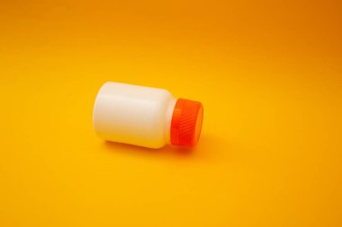 Sarı arka planda hapları olan kavanoz.