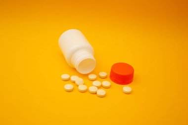 Sarı arka planda hapları olan kavanoz.