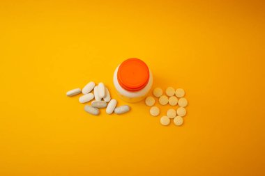 Sarı arka planda hapları olan kavanoz.