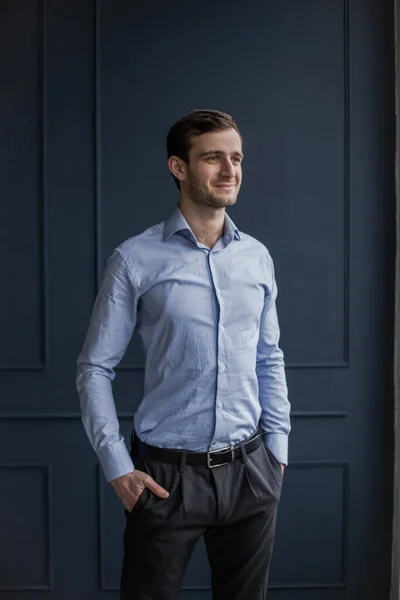 Gömlekli Gürcü bir adam mavi bir duvara karşı duruyor.