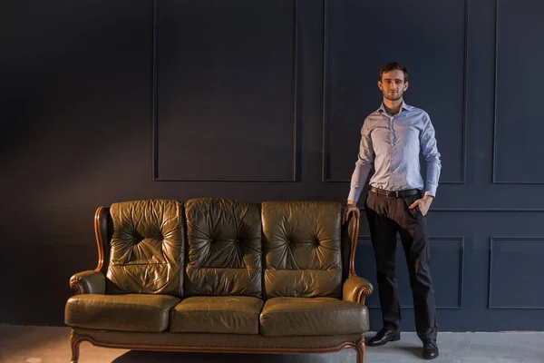 Eski bir kanepenin yanında gömlekli bir Gürcü.