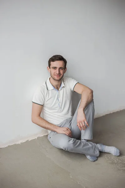 Man White Shirt Gray Pants Sitting Floor White Wall Monochrome — Fotografia de Stock