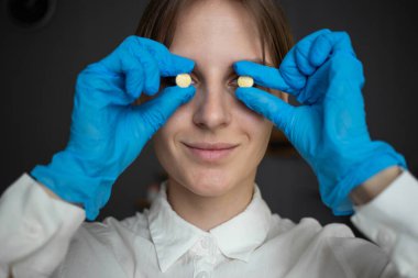 The nurse is holding pills instead of eyes